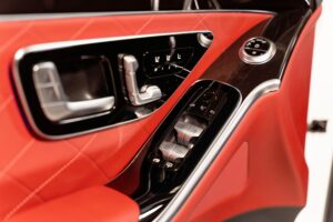 Close-up of a modern car door interior featuring red leather and sleek design elements.