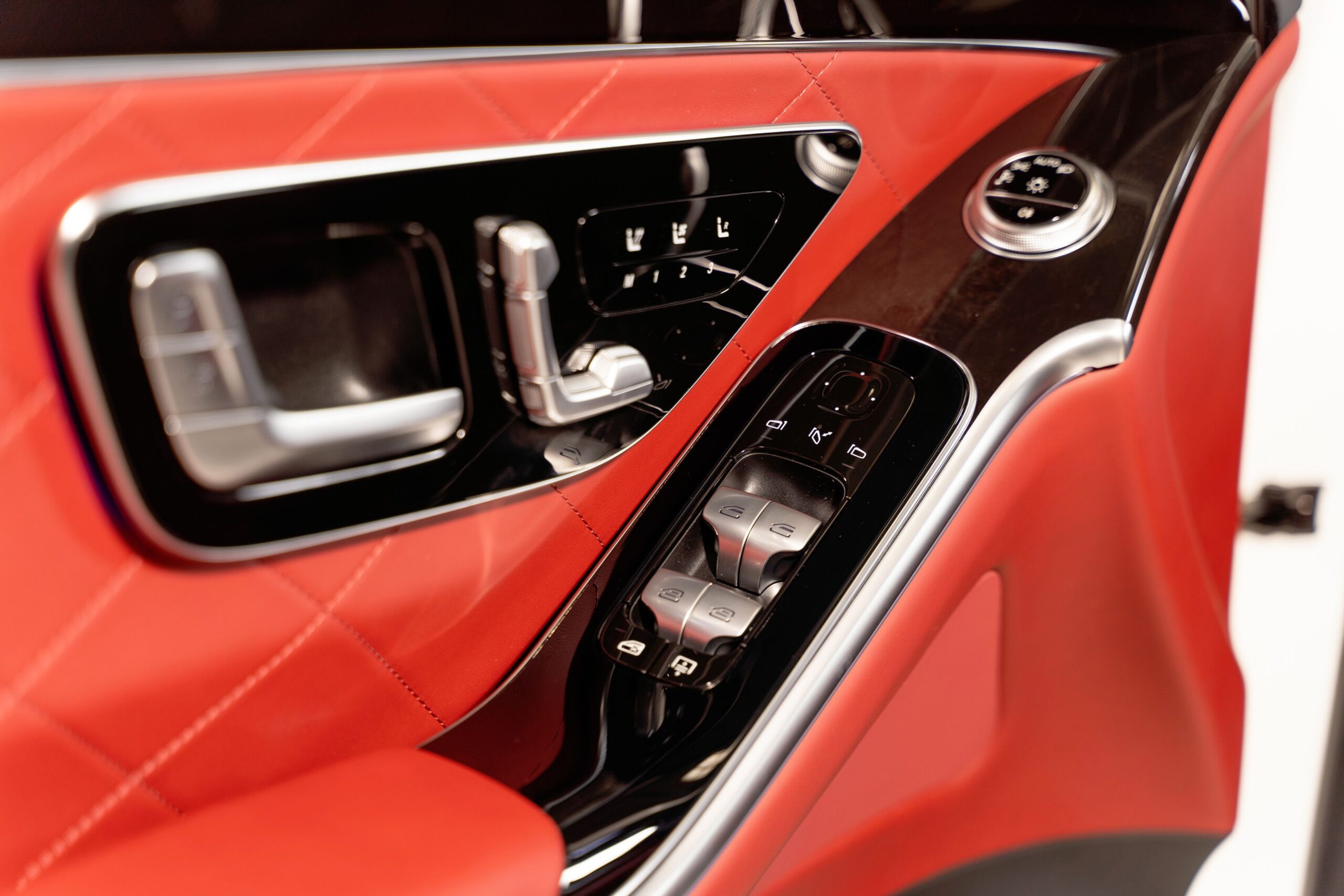 Close-up of a modern car door interior featuring red leather and sleek design elements.